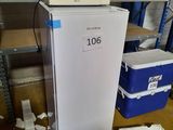 un micro-ondes posé sur un réfrigérateur dans une pièce