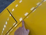 someone is pointing at the hood of a yellow car that has been painted