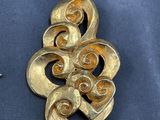 a gold brooch and a pair of shoes on a blue cloth