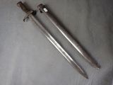 pair of old swords on a table with a cloth background
