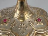 a gold candle holder with a red stone on top of it