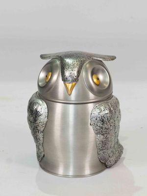 a silver owl figurine sitting on a white surface