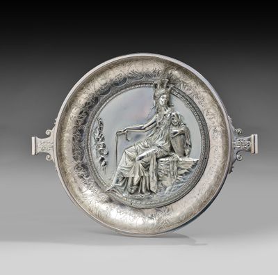 une image représentant une assiette en argent sur laquelle figure une femme assise à cheval