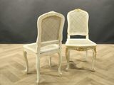 two white chairs sitting on top of a wooden floor next to a gray wall