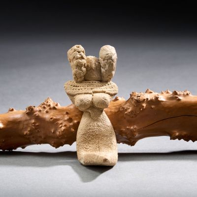 une figurine représentant une femme tenant deux oiseaux sur une branche