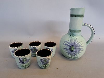 quatre tasses et un pichet posés les uns à côté des autres sur une table