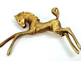 gold plated horse broochle on white surface with white background