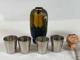 four shot glasses and a bottle of liquor next to a bottle opener