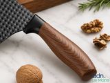 a wooden handle and a black handle on a cutting board with walnuts