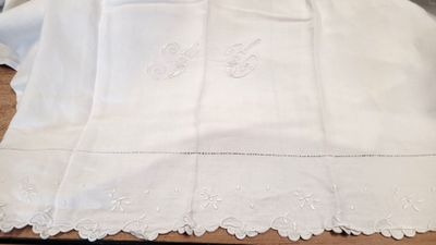 des nappes brodées posées sur une table en bois recouverte d'une nappe blanche