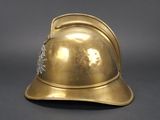 an antique brass fireman ' s helmet on a grey background