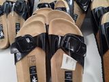 many pairs of black sandals that are on a table