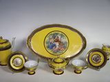 une assiette jaune ornée d'une image, posée à côté de tasses et de soucoupes