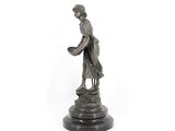 bronze statue of a woman holding a basket on a pedestal