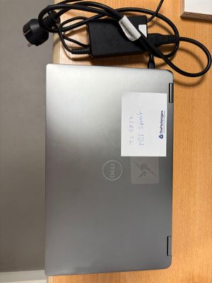 un ordinateur portable posé sur un bureau, avec son chargeur