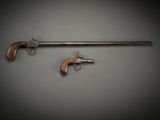 an old gun and a revolver on a gray background