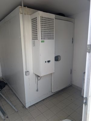 a small room with a refrigerator and a chair in it