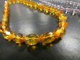 some yellow beads are sitting on a table with a silver chain
