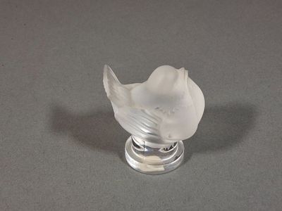un oiseau en verre posé sur un socle en argent