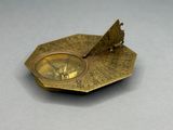 an old brass sundial on a gray surface with a white background