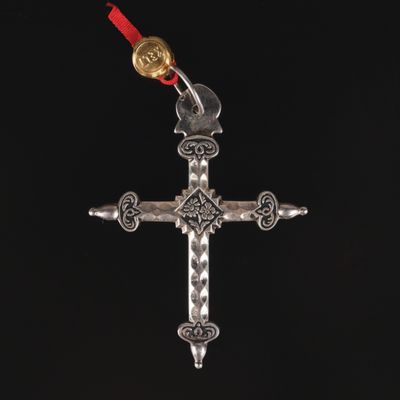 a silver cross with a red ribbon hanging from it