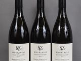 three bottles of wine are lined up on a table
