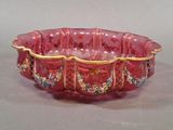 a red bowl with gold trimmings and flowers on it
