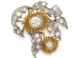 un gros plan d'une broche représentant des fleurs et des feuilles sur fond blanc