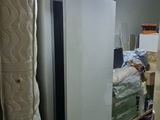 a refrigerator and a bed in a room with a lot of stuff
