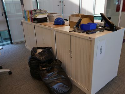 un sac poubelle posé par terre à côté d'un bureau