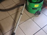 a green vacuum cleaner on the floor next to a green bucket