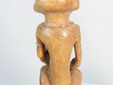 sculpture of a woman sitting on a stool with a hat on top of her head