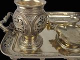 a silver tray with a silver cup and a silver plate on it