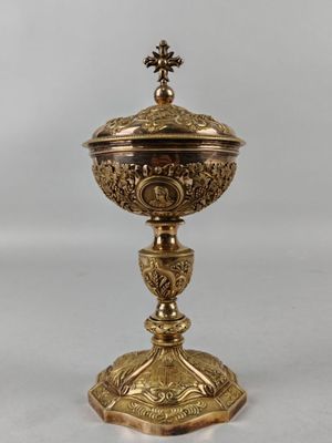 une coupe en or richement décorée, surmontée d'une croix