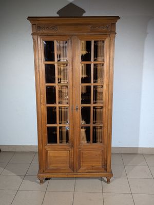 a tall wooden cabinet with glass doors in a room