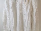 a white blouse hanging on a hanger on a wall