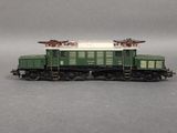 a green and white train on the tracks on a gray surface