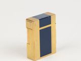 un briquet doré et bleu posé sur une surface blanche