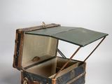 une vieille valise avec un couvercle en verre, posée sur une surface blanche