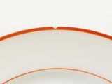 a white plate with orange rim on a white table