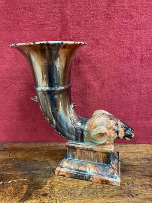 a horn shaped vase sitting on a wooden table