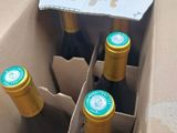 six bottles of wine in a cardboard box on a table