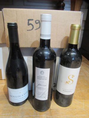 trois bouteilles de vin posées sur une table à côté d'une boîte