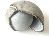 une boule en pierre percée d'un trou, posée sur une surface blanche
