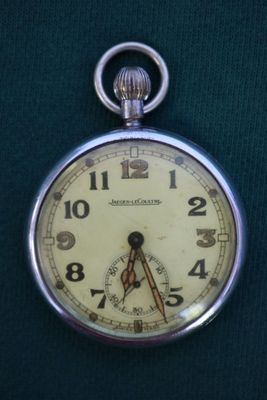 a silver pocket watch with a white face on a green cloth