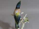 a figurine of a bird sitting on a tree branch
