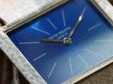 a close up of a watch with a blue face