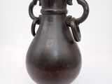 un vase noir posé sur une surface blanche
