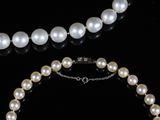 pearl necklace and bracelet on a black surface with a black background