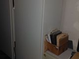 a white refrigerator in the corner of a room next to a desk